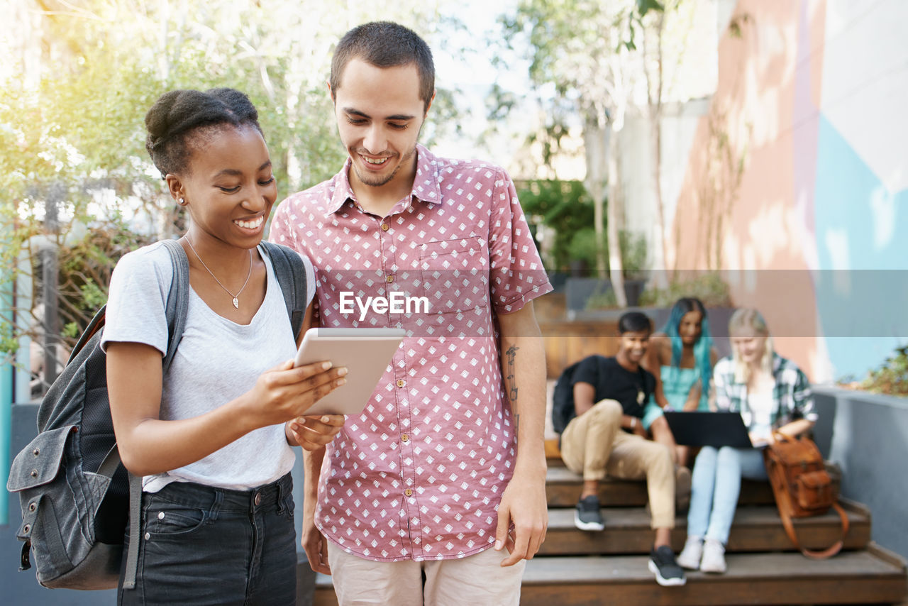 Smiling friends looking at digital tablet