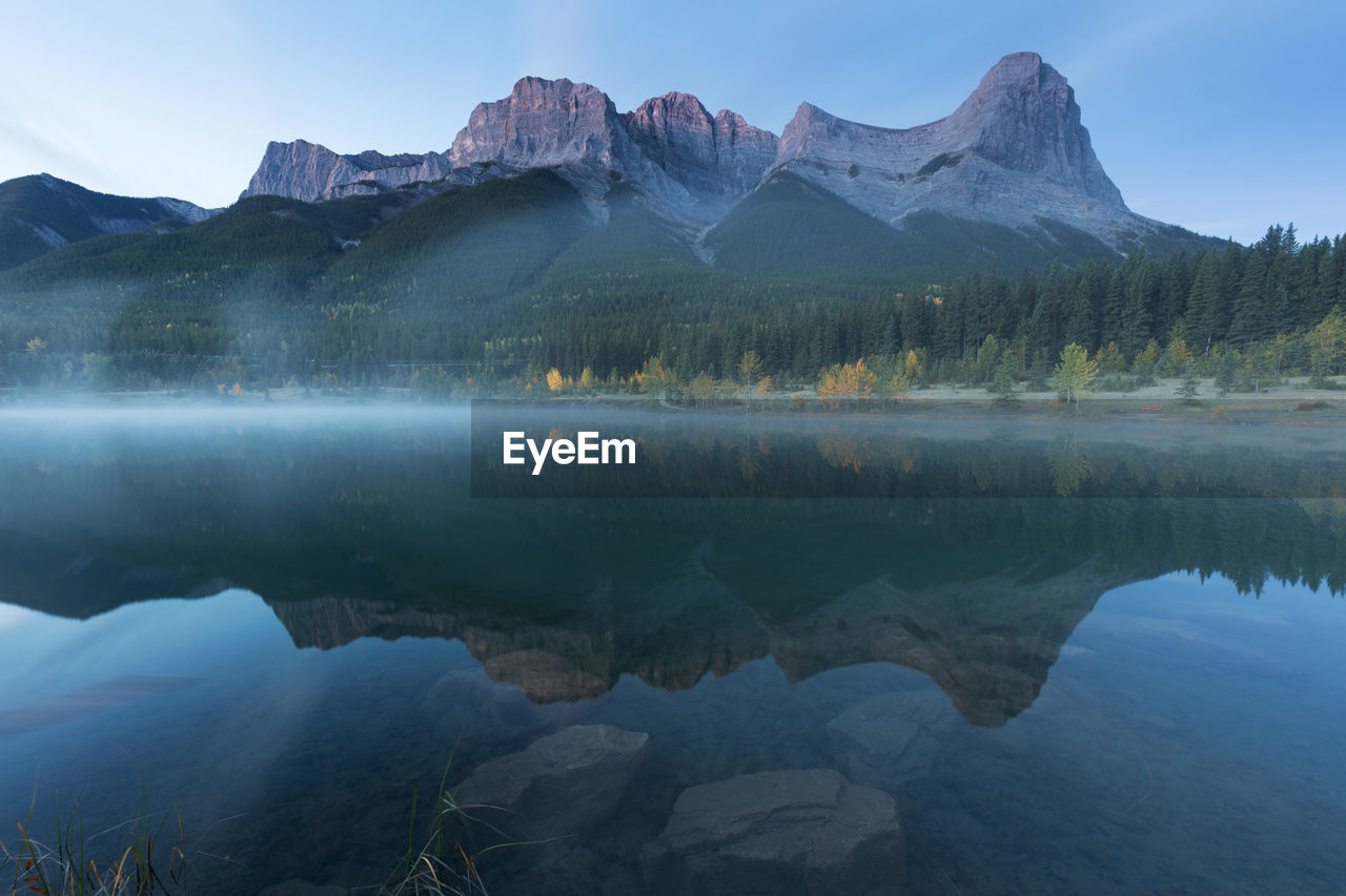 REFLECTION OF MOUNTAINS IN LAKE AGAINST SKY