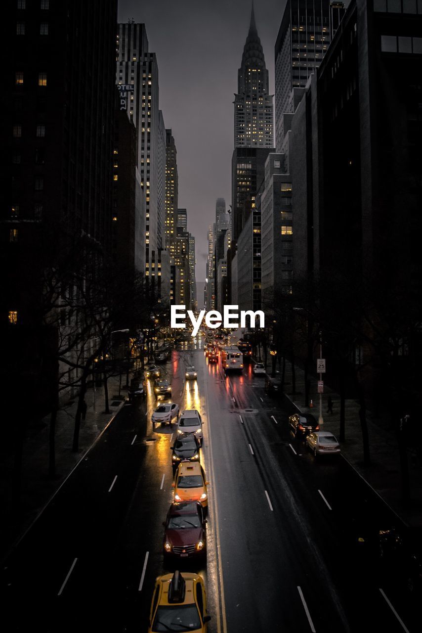 Traffic on city street amidst buildings at night