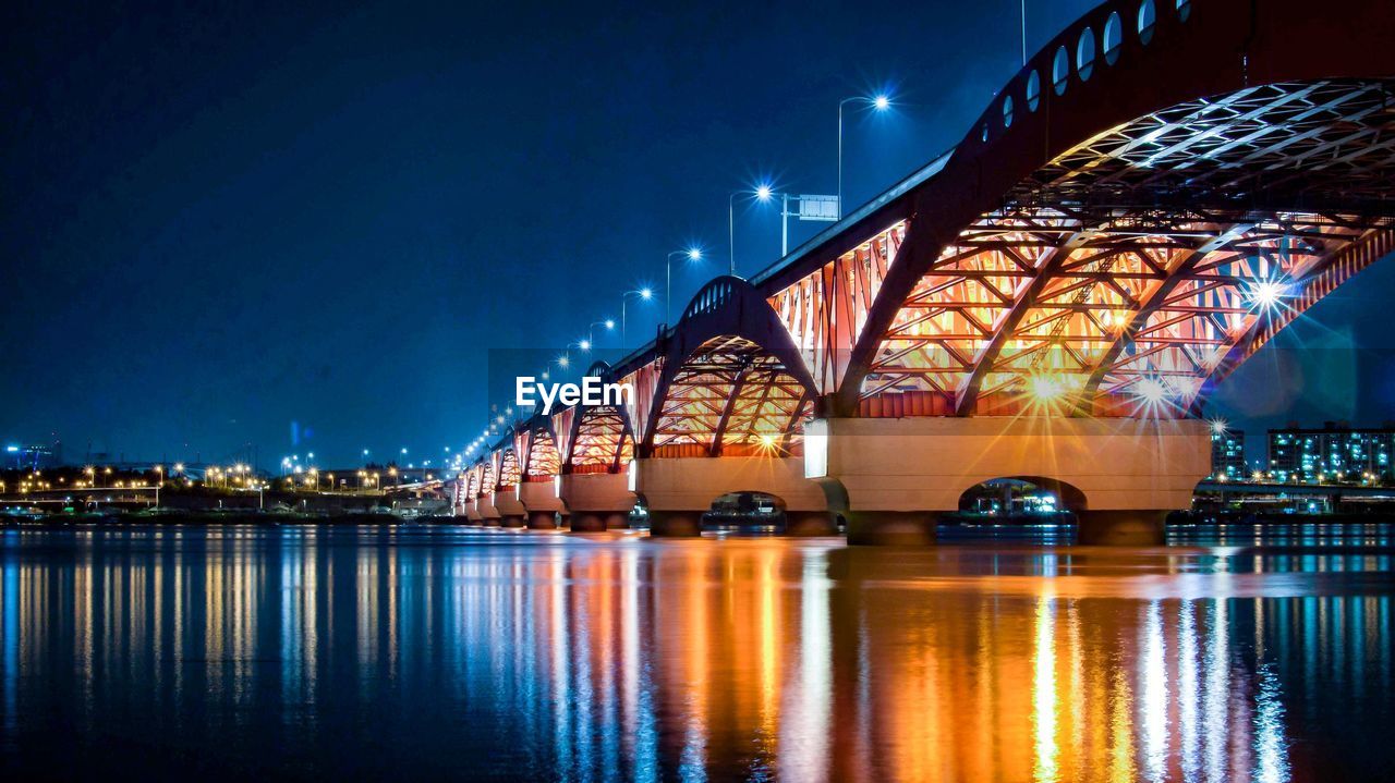 Illuminated bridge over river at night