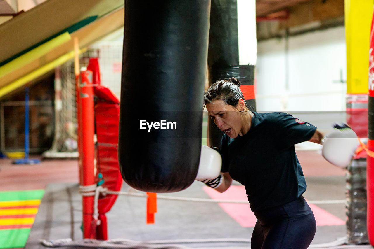 Female boxer hitting a huge punching bag at a boxing studio.