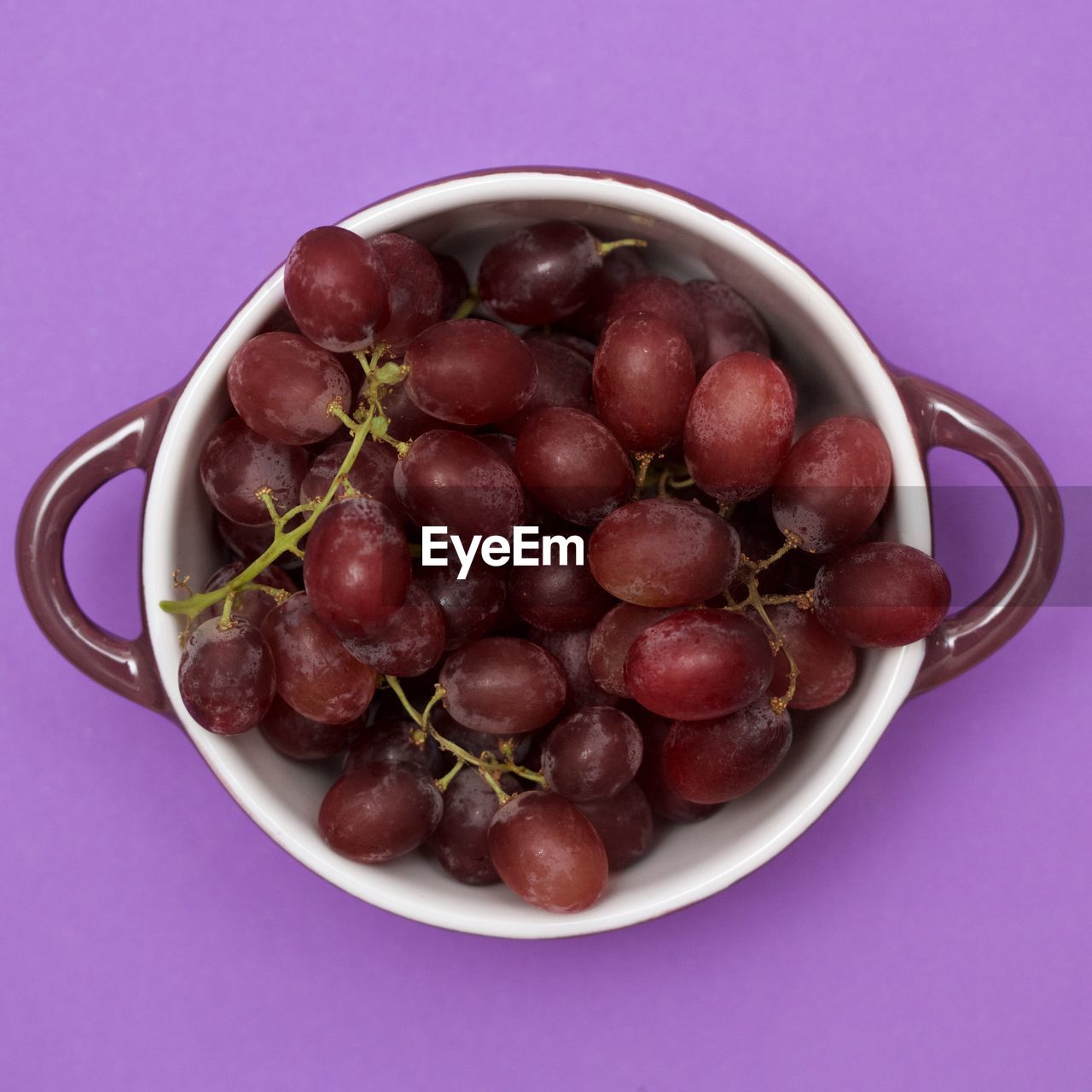 Directly above shot of grapes in bowl on purple table