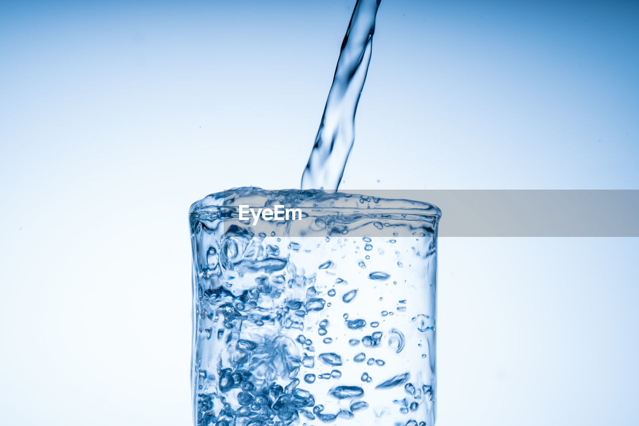 blue, water, studio shot, soft drink, refreshment, food and drink, drink, indoors, household equipment, drinking glass, no people, cobalt blue, cold temperature, blue background, freshness, colored background, glass, splashing, motion, lighting, drop, nature, pouring, cold drink, transparent, close-up, copy space, simplicity, single object, drinking water, bubble, food