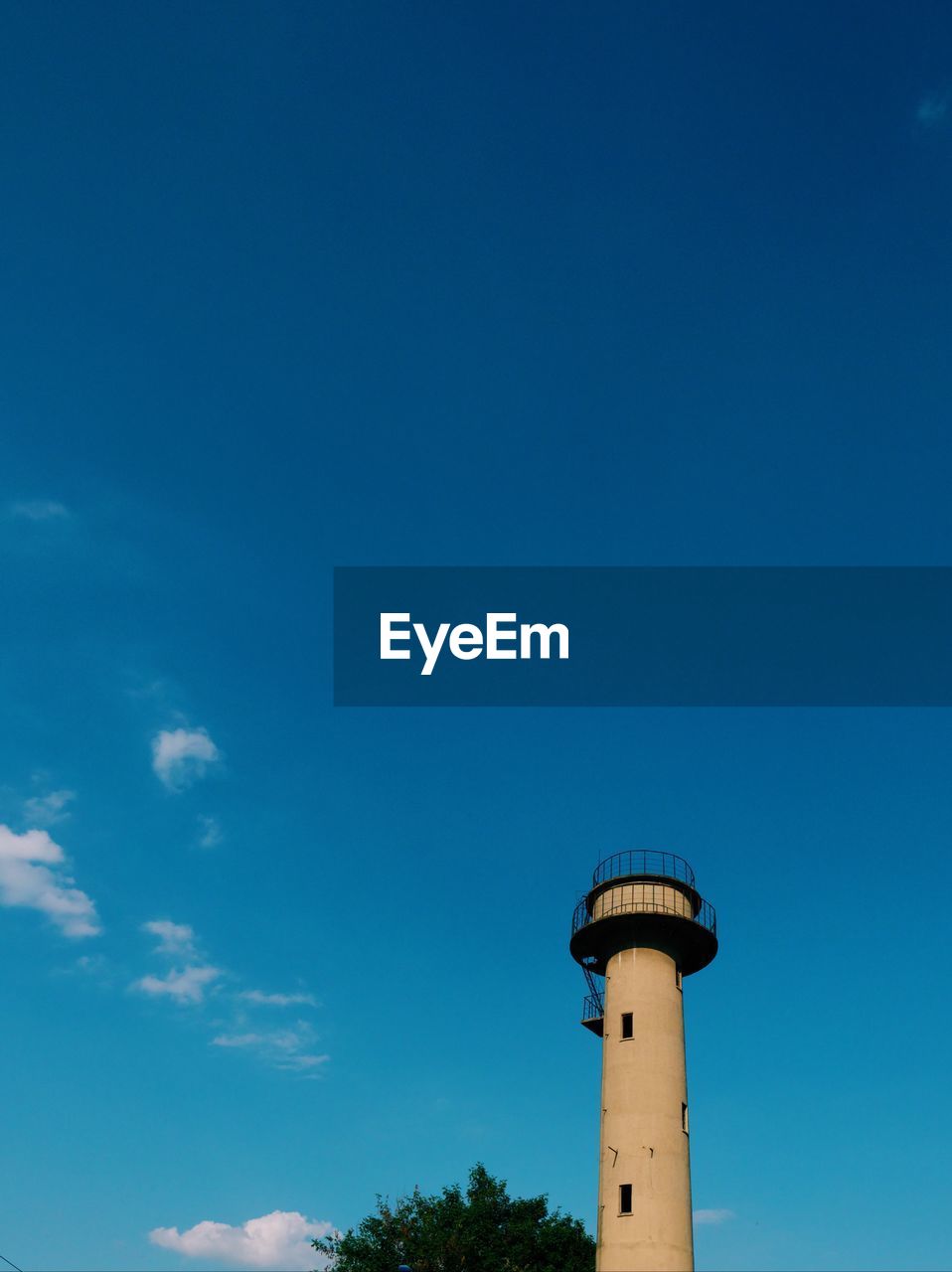 LOW ANGLE VIEW OF WATER TOWER AMIDST PLANTS AGAINST SKY