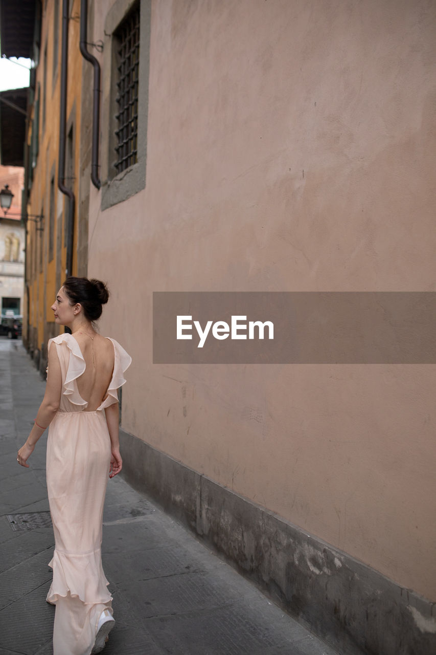 Rear view of beautiful women walking on street by building