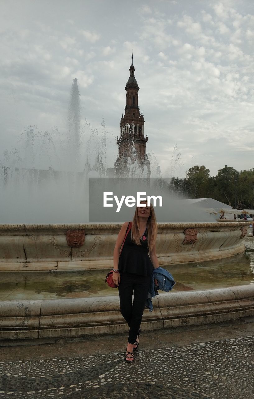 Full length of woman standing against fountain in city