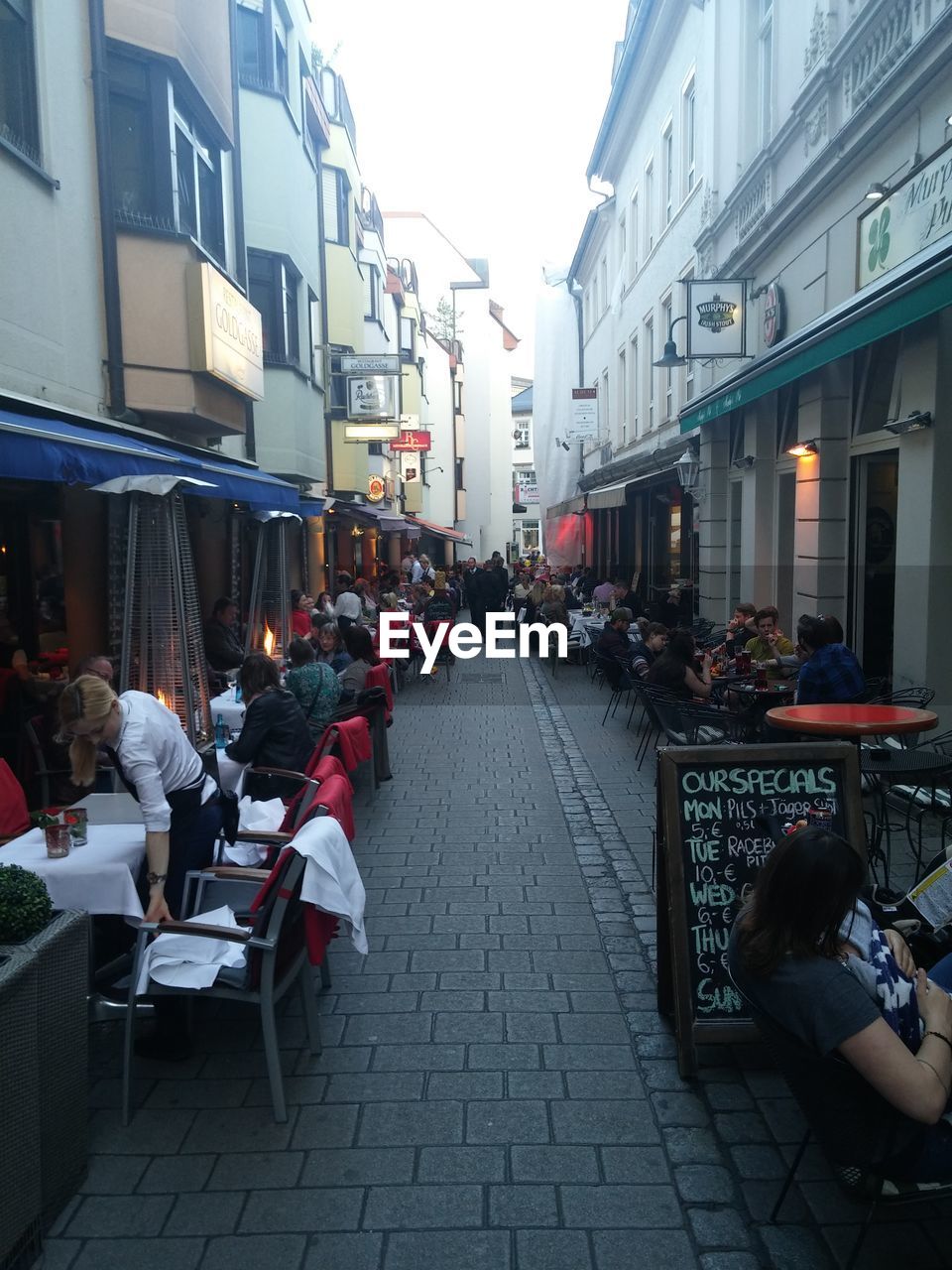 People at sidewalk cafe amidst buildings