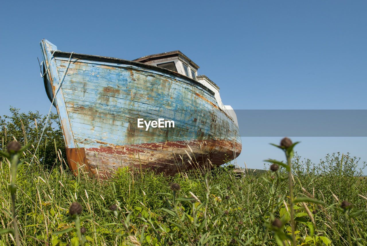 Abandoned boat on field against clear sky