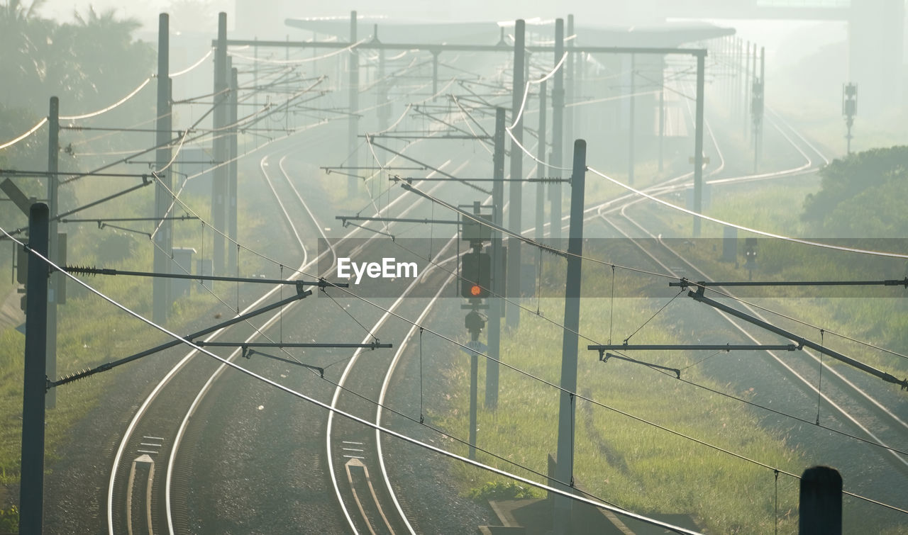 transportation, fog, electricity, nature, line, no people, transport, architecture, day, mode of transportation, track, railroad track, sky, sign, built structure, outdoors, technology, road, rail transportation, travel, cable, city, electricity pylon