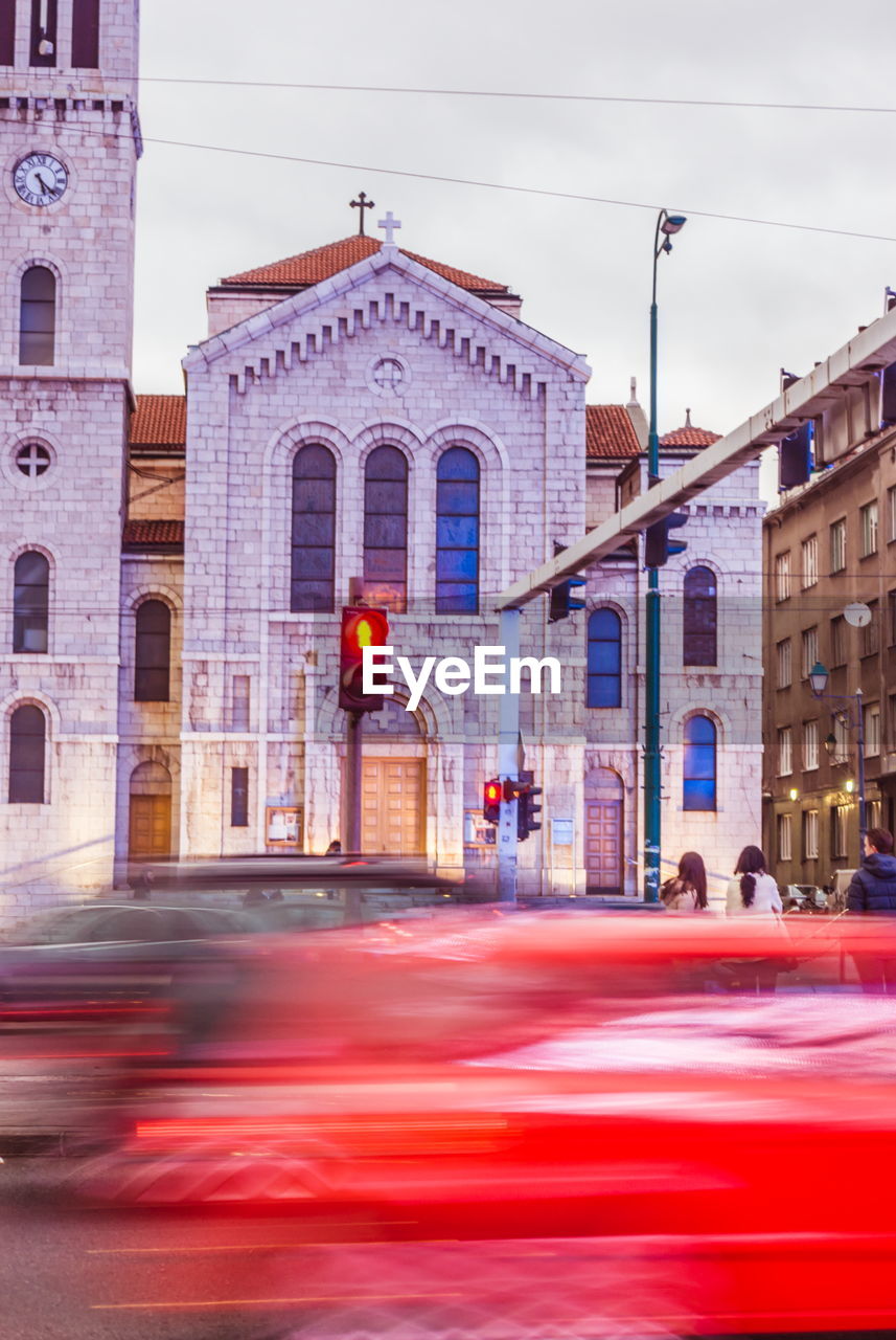 Blurred motion of cars and people on street against buildings in city