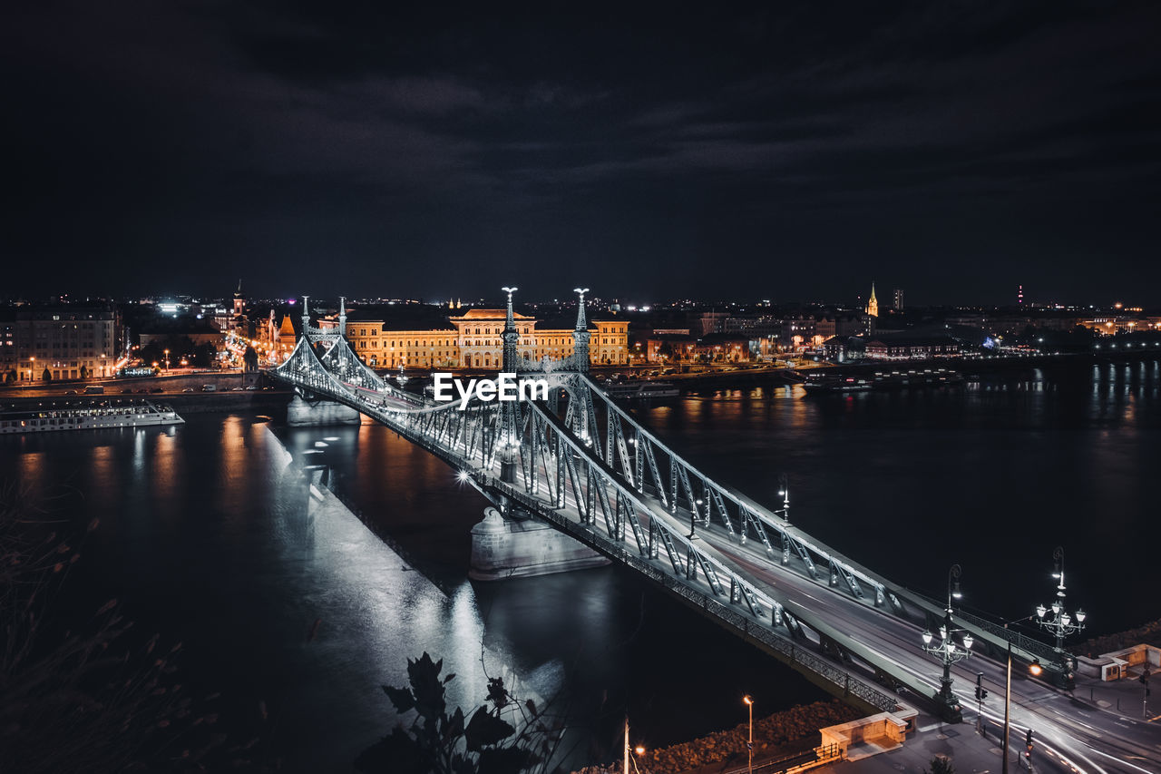 Illuminated bridge over river at night