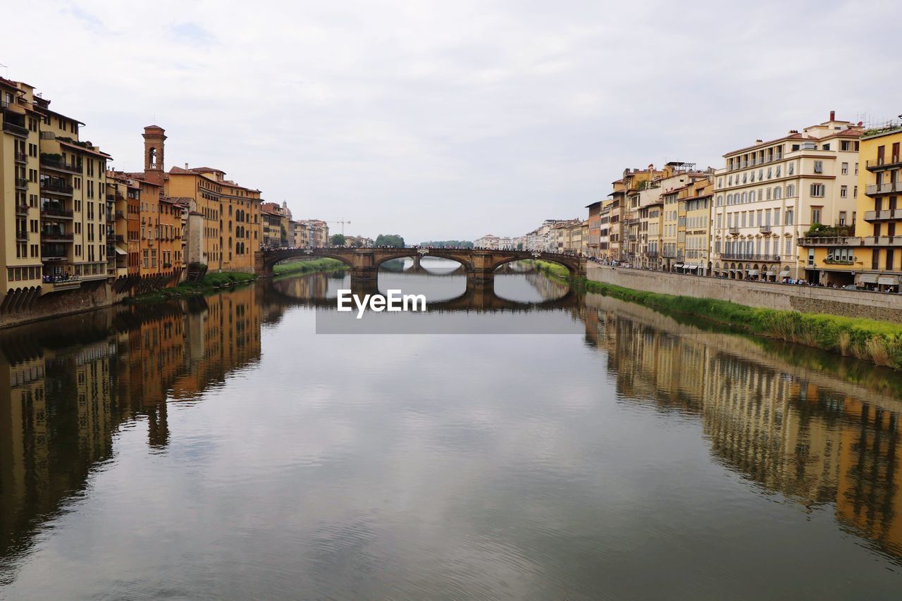 Reflection of buildings on river against sky in city