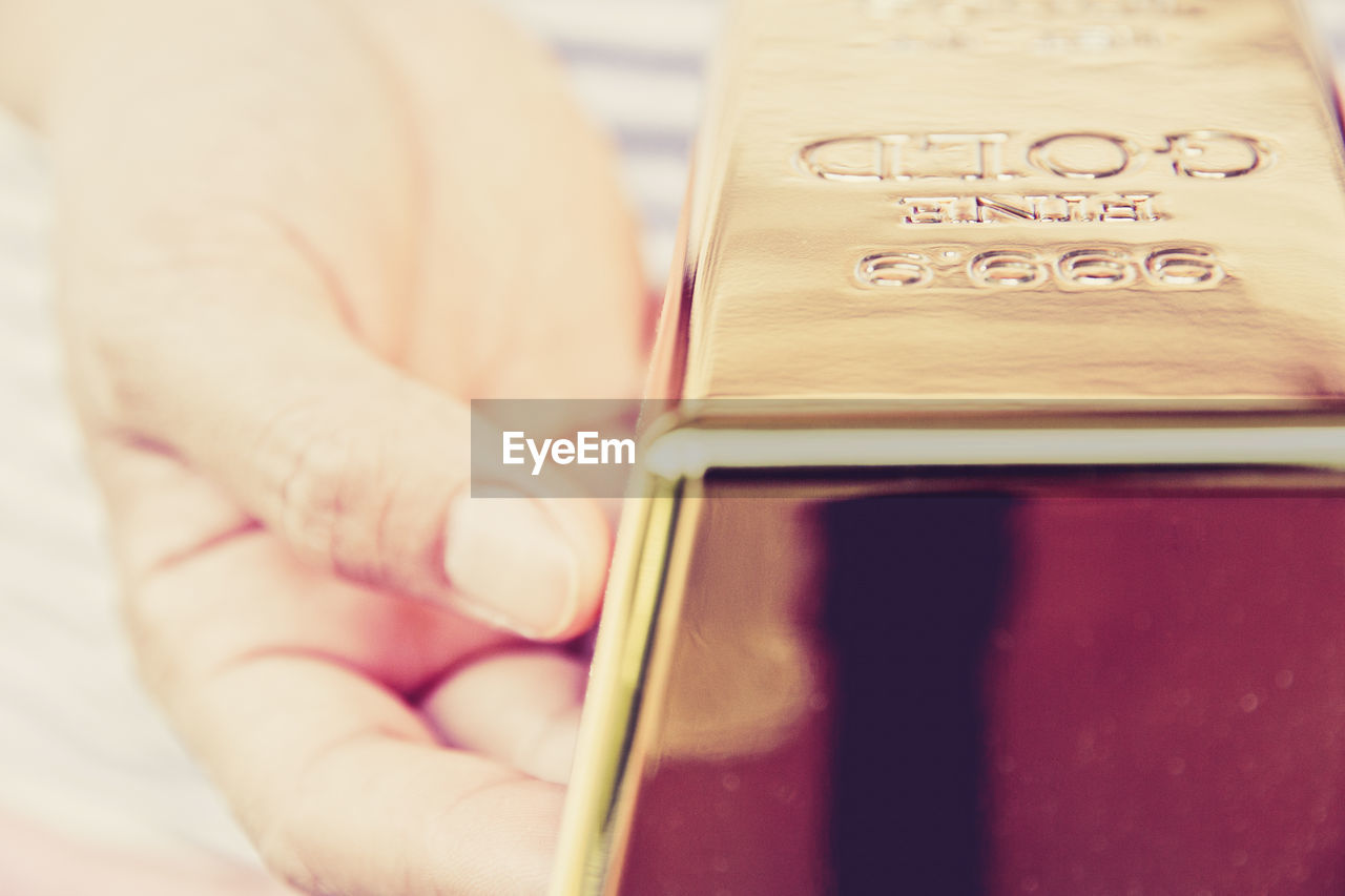 Close-up of hand holding gold bar