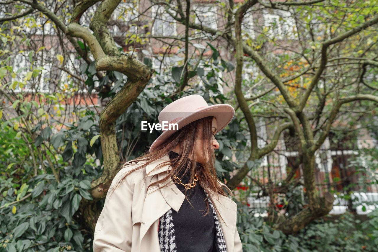 Woman standing by tree against plants