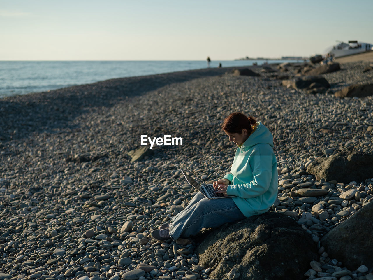 Caucasian woman working freelance on laptop on the beach