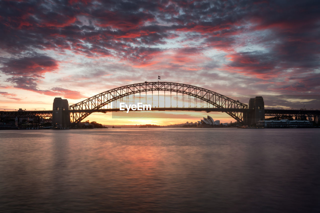 Illuminated bridge over river against sky at night