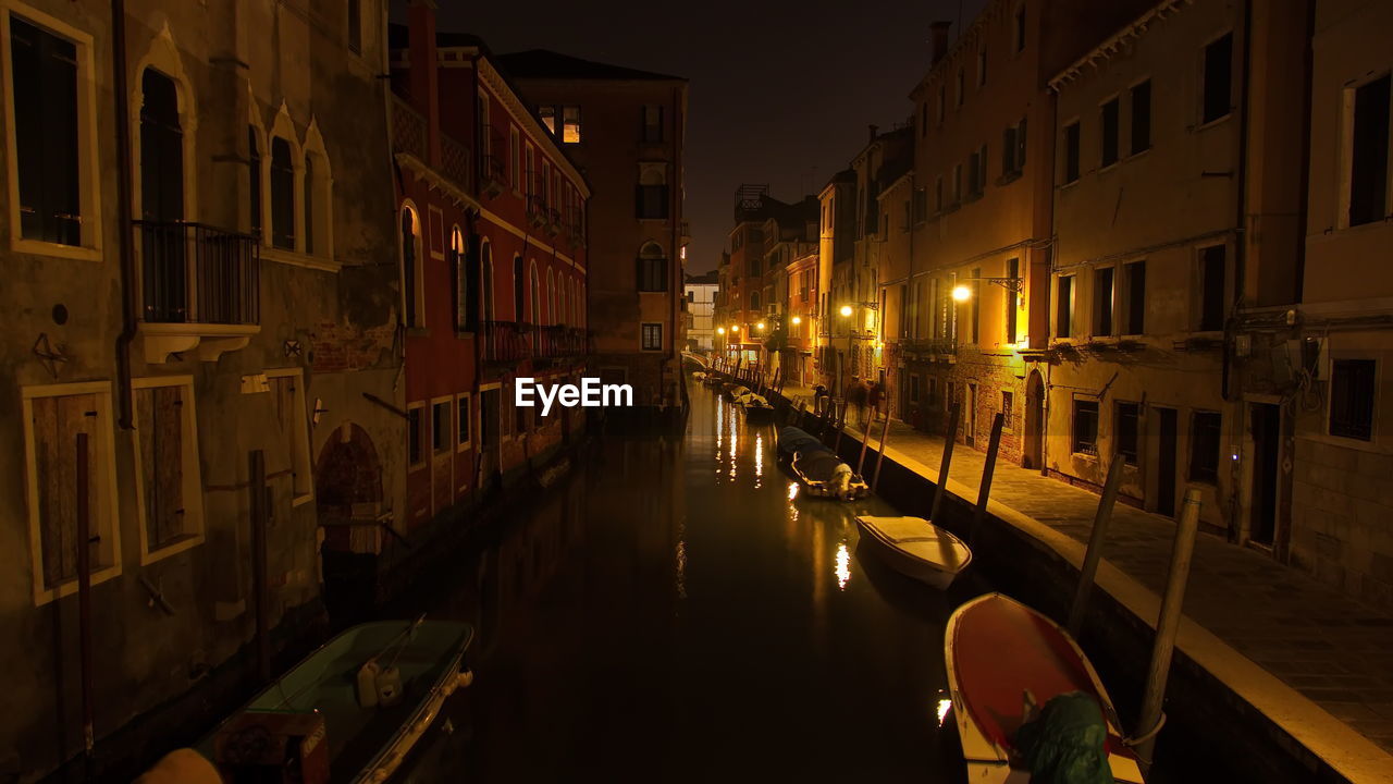 Canal amidst buildings in city at night