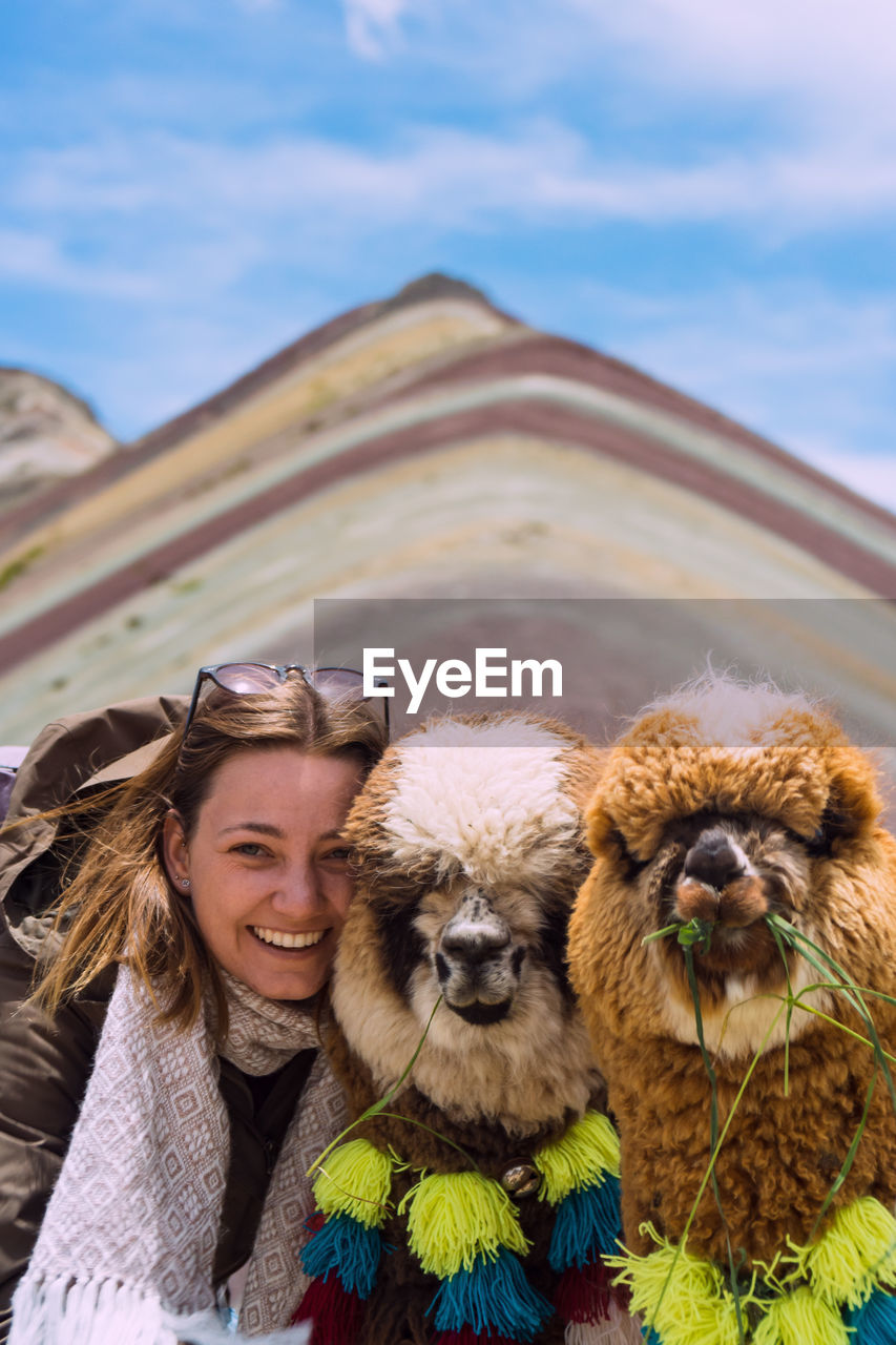 Portrait of smiling woman with mammals against mountains