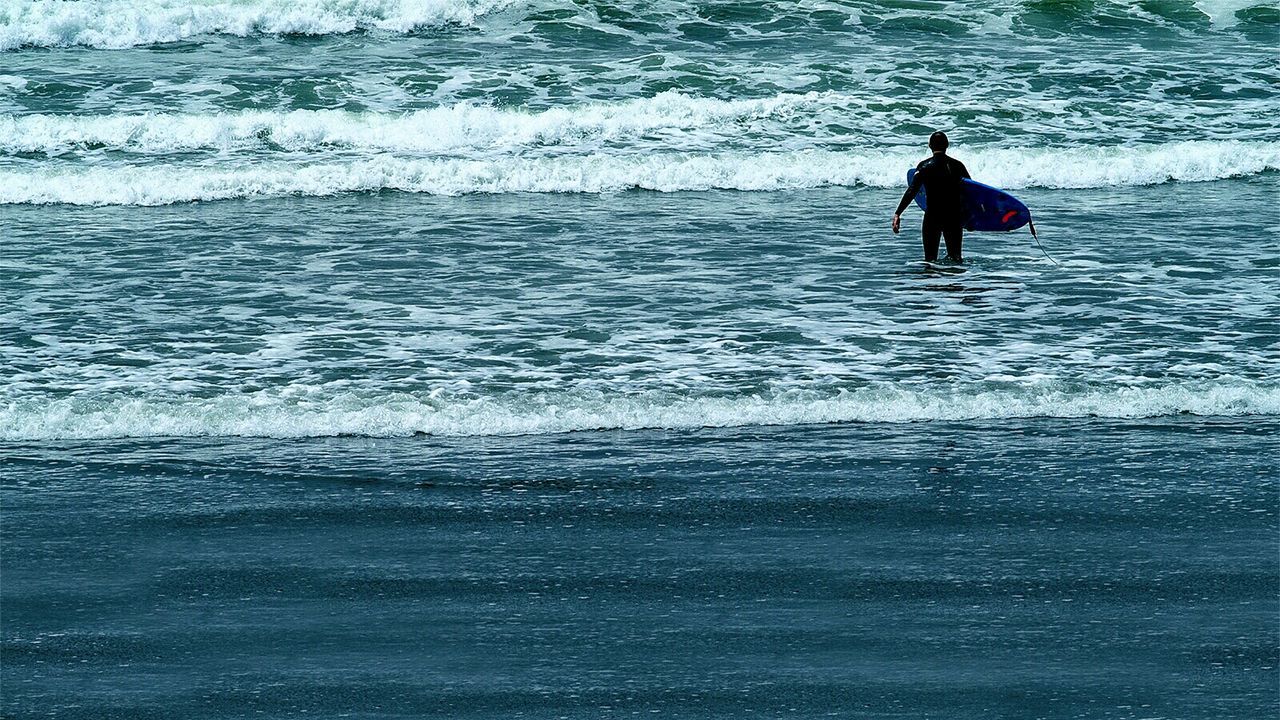 Surfer with surfboard walking on beach