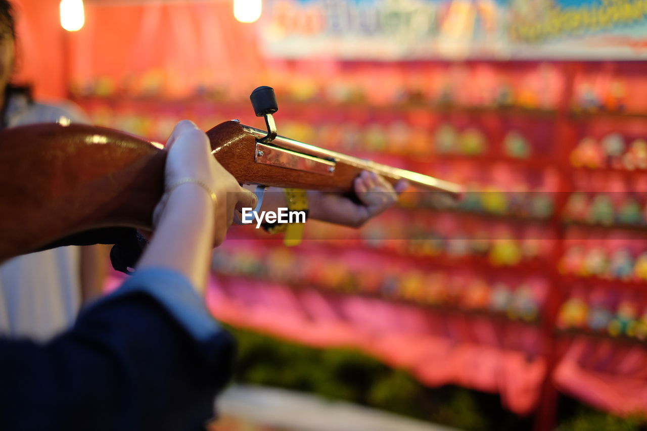 Cropped image of hands aiming target at carnival booth