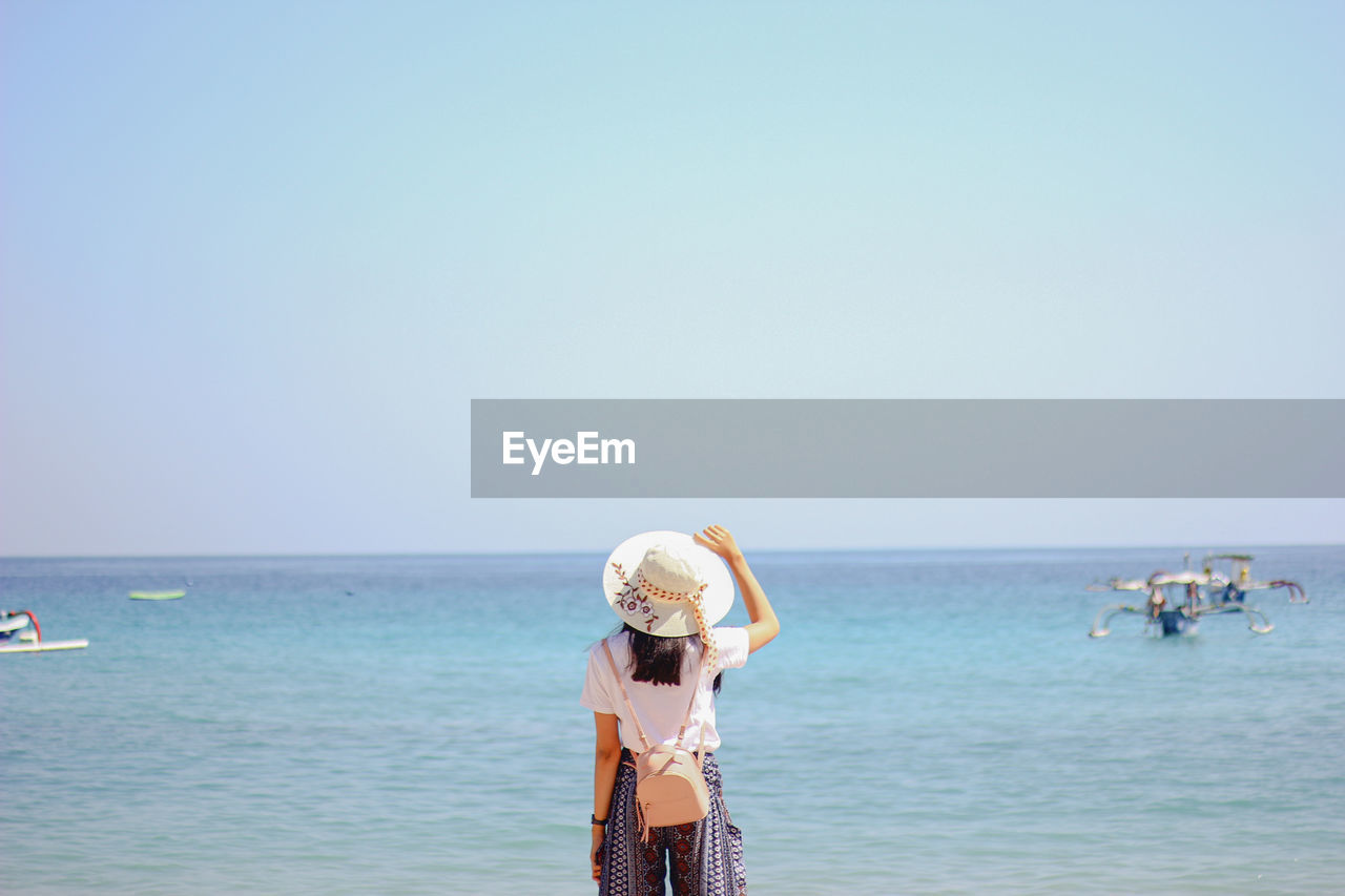 People standing on beach against clear sky