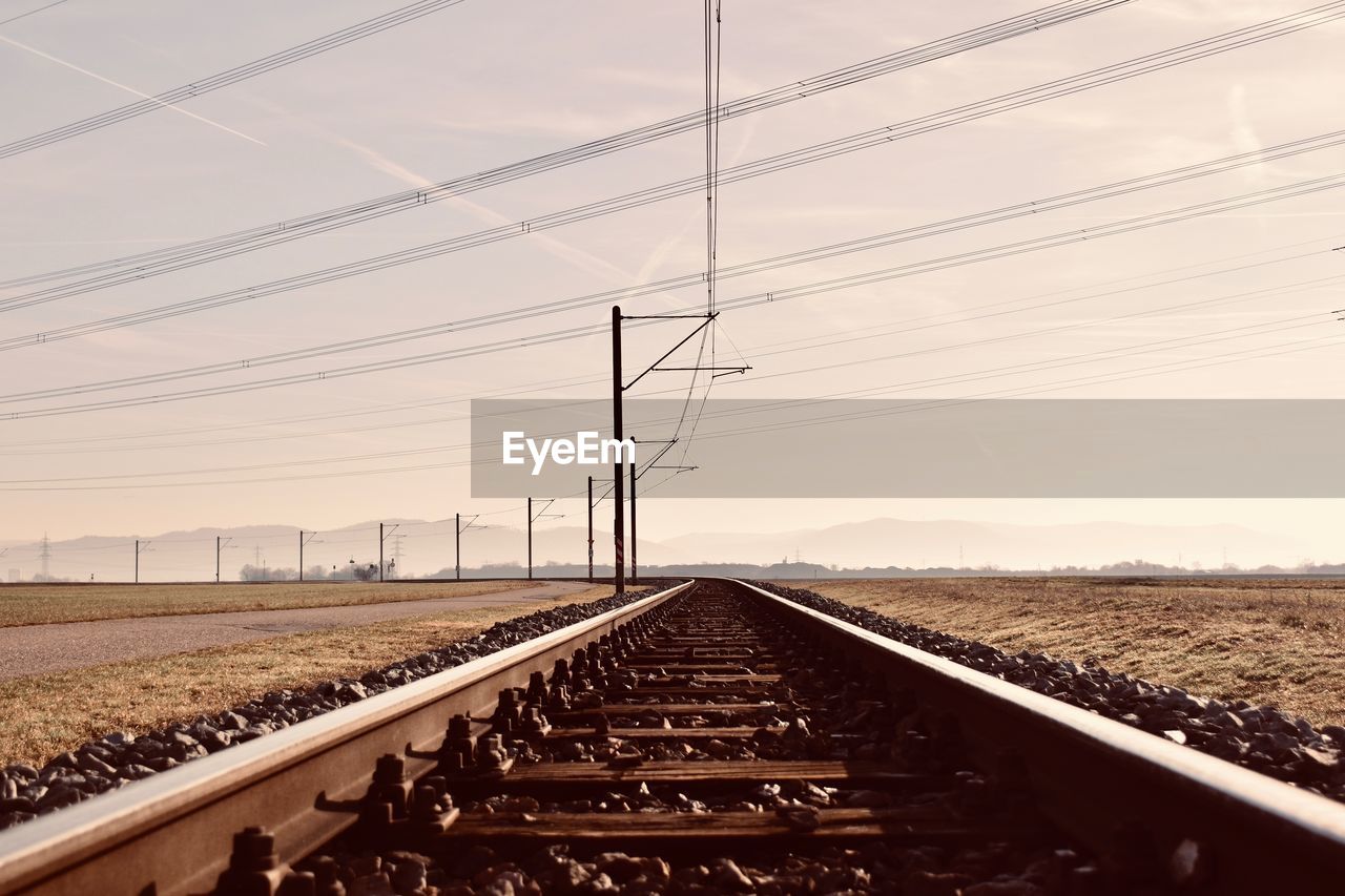 RAILROAD TRACK BY ELECTRICITY PYLON AGAINST SKY