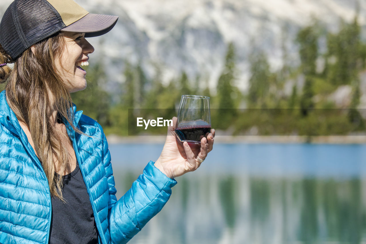 Young active attractive woman enjoys red wine at the lake.