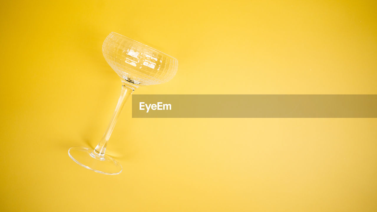 A coupe glass on a bright yellow background