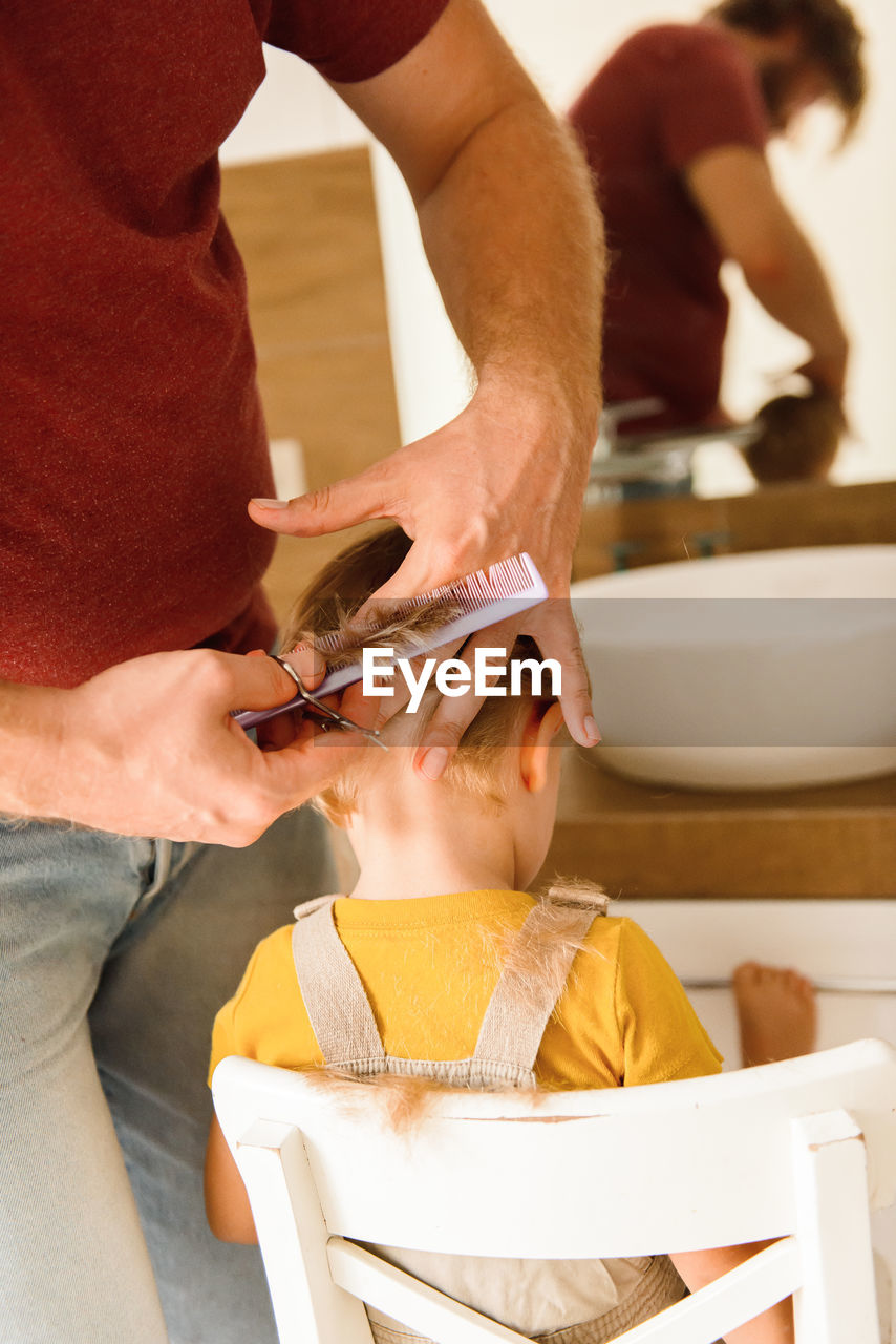 Dad cutting hair to little son