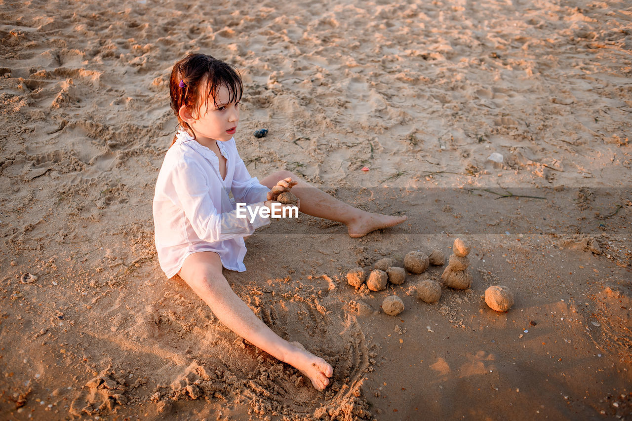 high angle view of girl playing with sand at beach