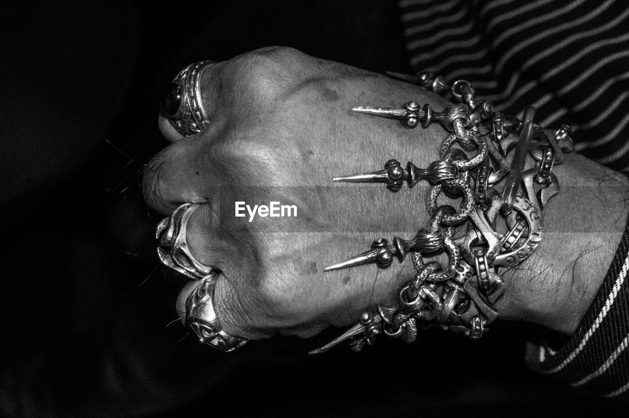 Close-up of man wearing various bracelet against black background