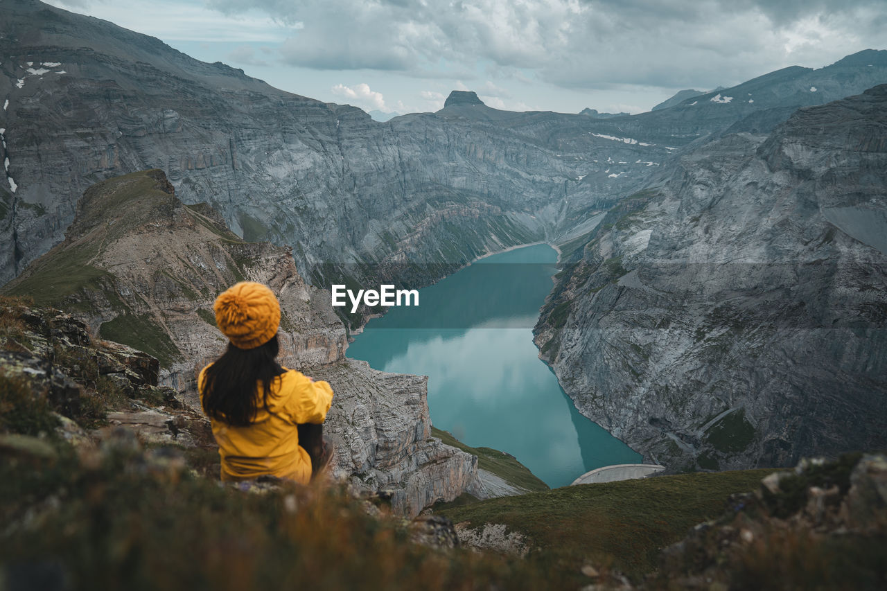 Young woman in yellow jacket looking at view in glarus, limmernsee lake