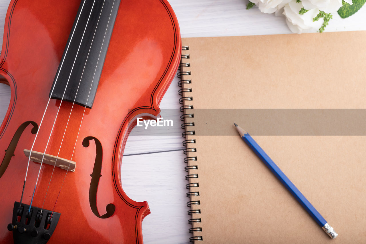 High angle view of violin by spiral notebook and pencil on table