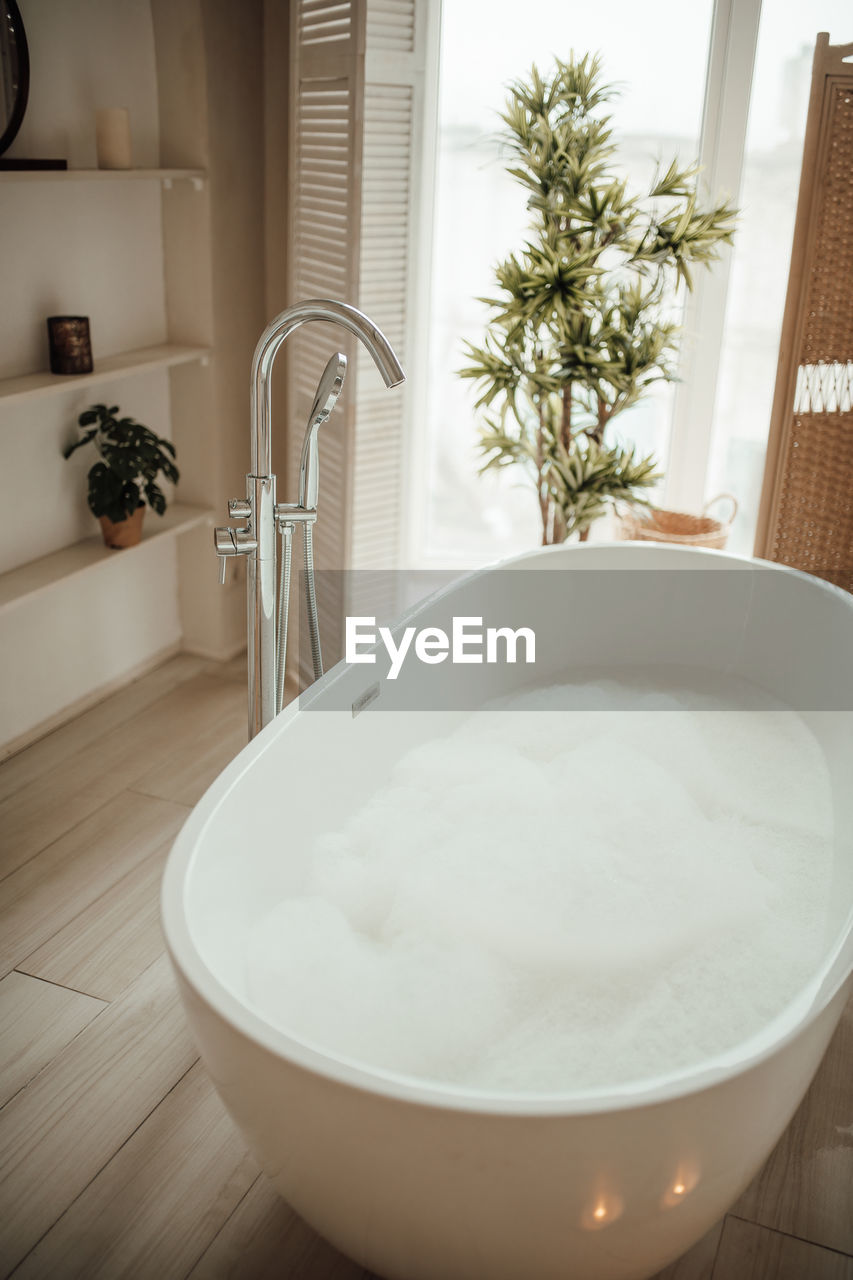 domestic room, home, bathtub, indoors, home interior, bathroom, domestic bathroom, room, household equipment, luxury, lifestyles, hygiene, wealth, nature, no people, faucet, white, flooring, domestic life, home showcase interior, plant, wellbeing, plumbing fixture, food and drink, sink, window, floor, bidet