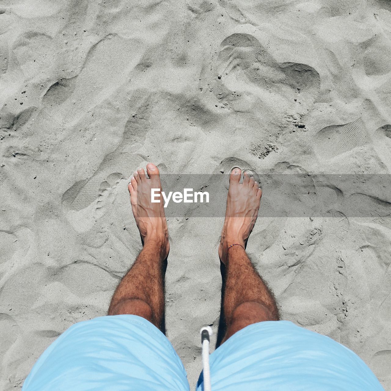 Low section of man standing on sand at beach