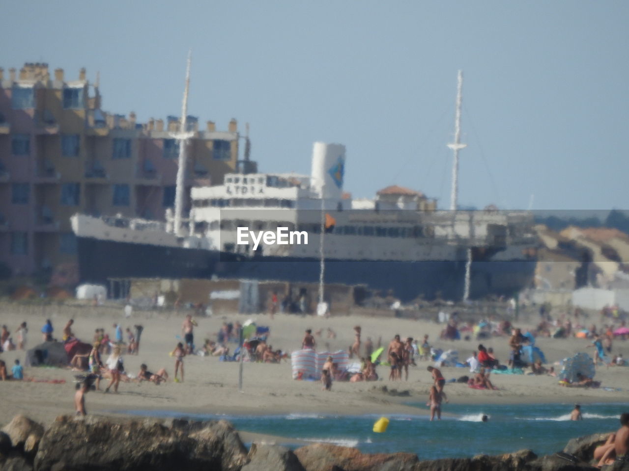 CROWD ON BEACH AGAINST SKY