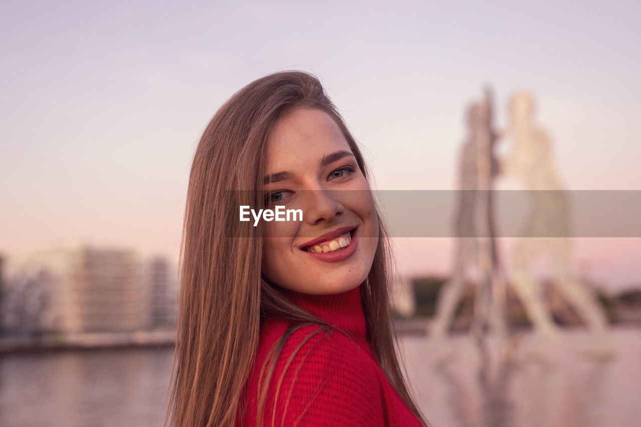 Portrait of smiling young woman against clear sky during sunset