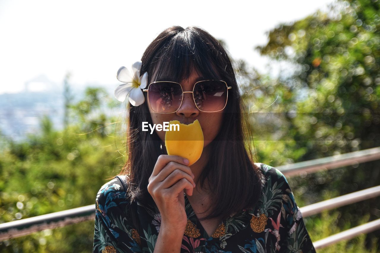 Portrait of young woman holding mango