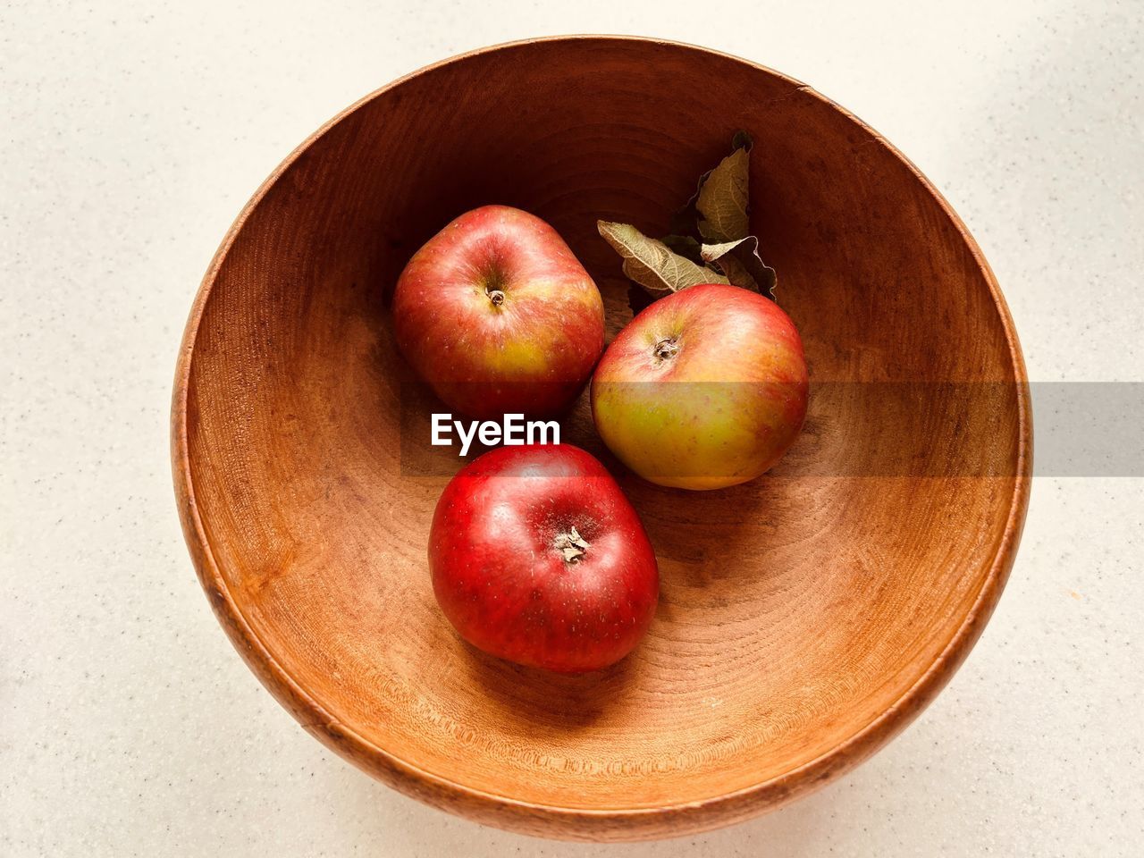 Three apples in  wooden bowl. red and green apples. foraged  in community orchard. fresh and juicy.