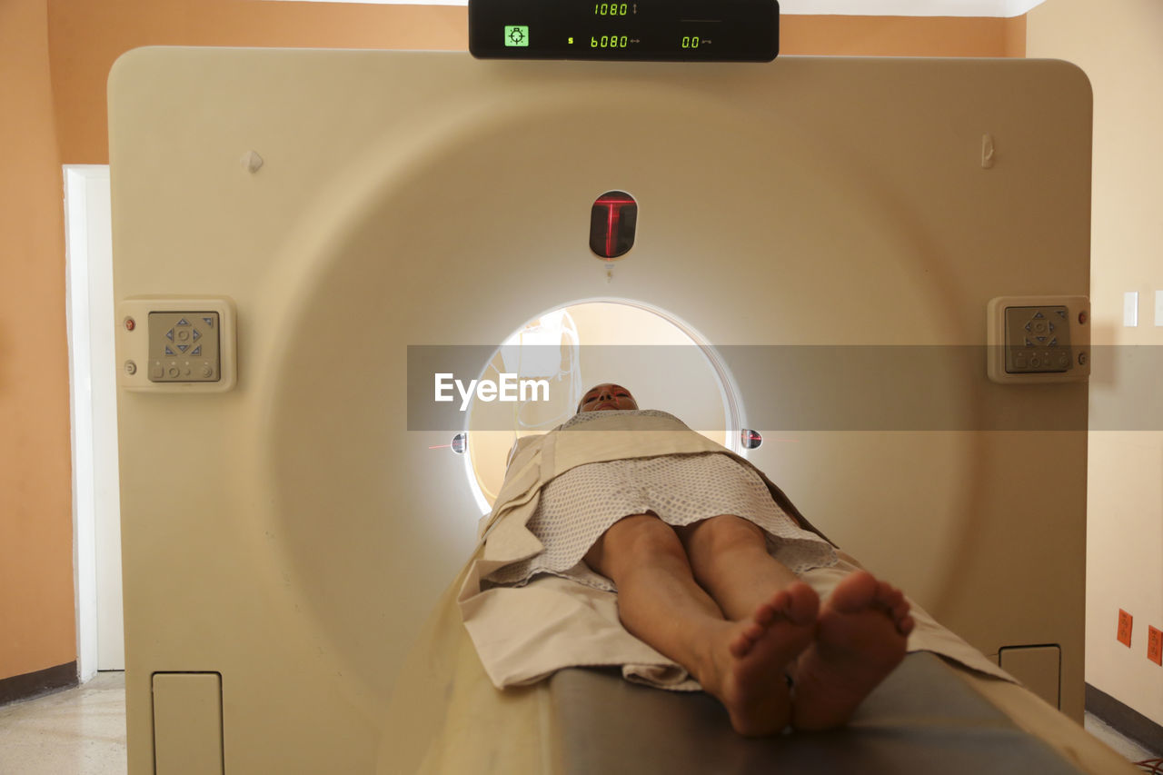 Patient lying at entrance of cat scan machine in medical examination room