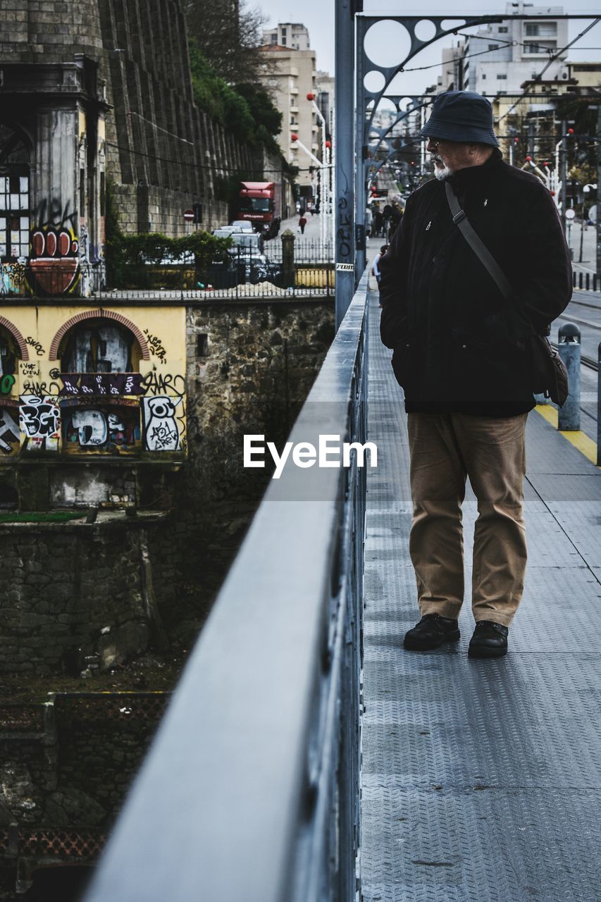 FULL LENGTH OF MAN WITH UMBRELLA ON CITY