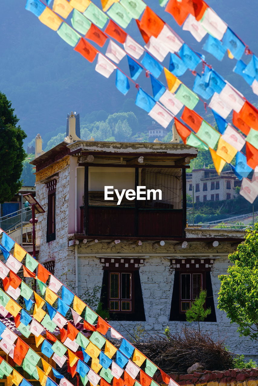 Multi colored tibetan flags hanging outside building against sky