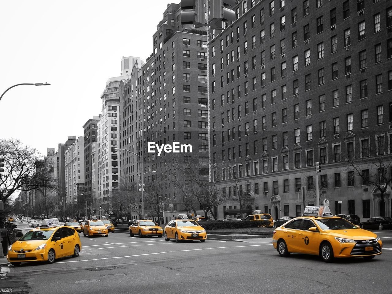 Yellow taxis on city street by buildings at midtown manhattan against clear sky