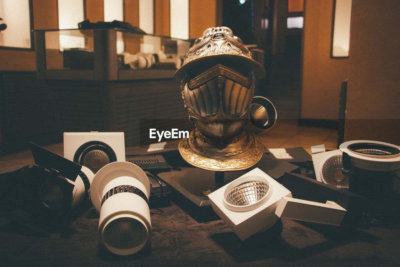 Close-up of ancient helmet and lighting equipment on table