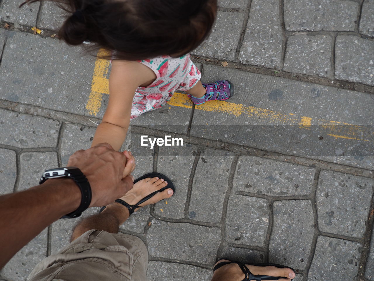 High angle view of girl  holding hands with man on cobblestone streets
