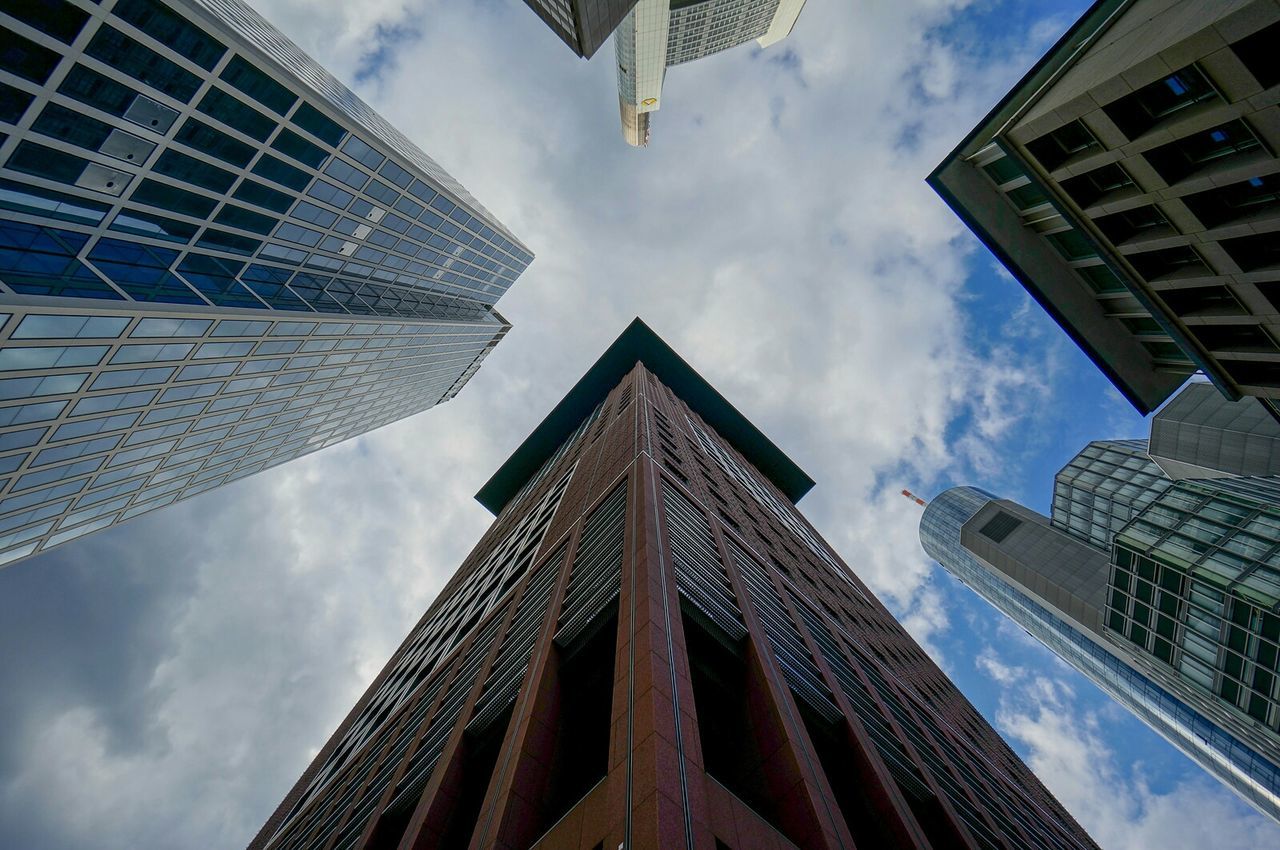 Directly below shot of buildings against cloudy sky