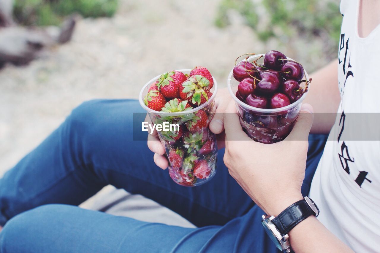 Midsection of man holding fruits in glass