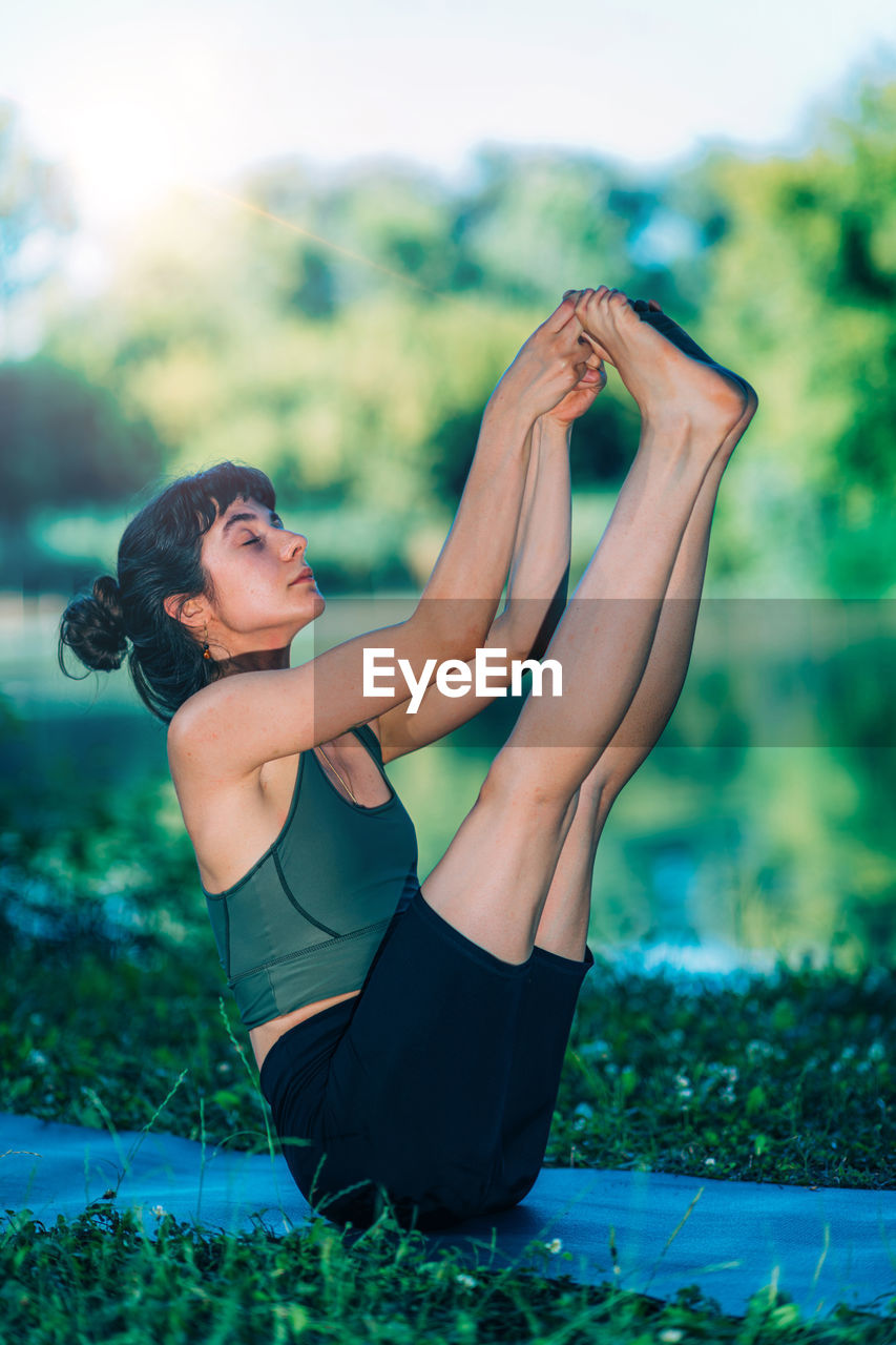 Yoga woman by the water. boat pose