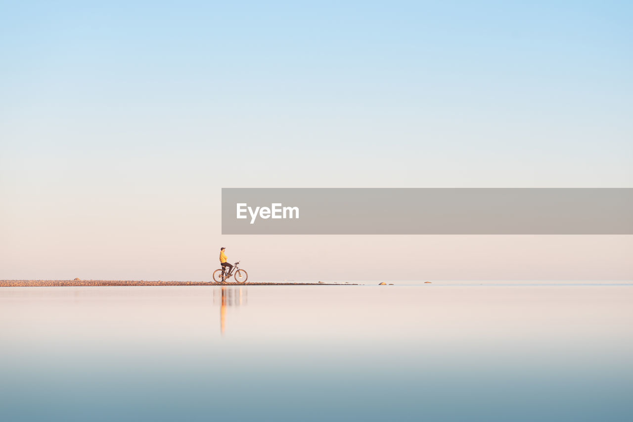 Cyclist on the shore of the calm sea. distant plan