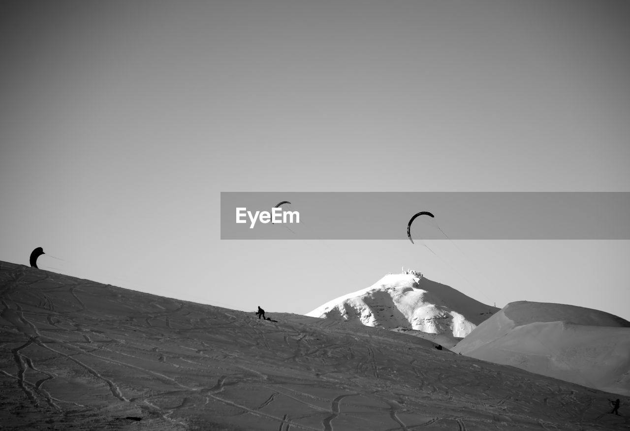 People on snowcapped mountain against clear sky